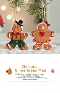Close-up of resin gingerbread man and woman hanging ornaments on a snowy pine tree