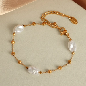 Elegant gold stainless steel bracelet featuring irregular white pearls on a textured background