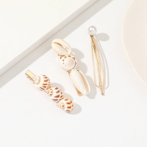 Macro detail of hair clips set featuring natural seashells, white pearl and golden metal frame
