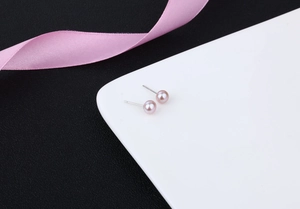 Close-up of elegant pink freshwater pearl earrings with silver posts on white tray