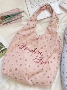 Tragetasche aus Segeltuch mit rosa Blumenmuster und roter Schrift auf einem Schreibtisch