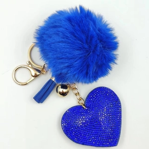 Detail of blue plush fur pompom with rhinestone heart charm and decorative tassel keychain