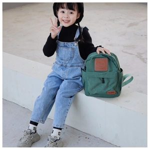 Close-up of deep green canvas kid's backpack with brown leather smiley face patch and label