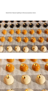 Detail shot of round enamel stud earrings in brown, yellow, and white with gold accents