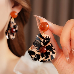 Close-up of leopard print flower earrings with resin petals and orange bead studs