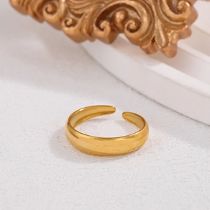Macro detail of 18K gold plated stainless steel open ring on elegant white textured surface