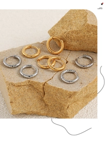 Detailed view of textured gold and silver hoop earrings on natural stone display