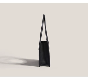 Side view of a black leather tote bag with long handles and a minimalist chic design