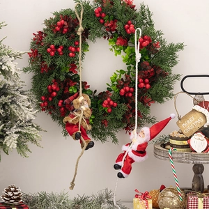 Christmas wreath with red berries and two climbing Santa Claus figurines on a hemp rope