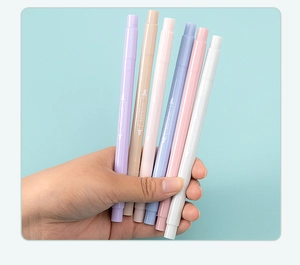Macro shot of hand holding dual-tip highlighters in soft Morandi pastel colors