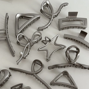 Macro view of silver-colored metal hair clips in butterfly and geometric shapes