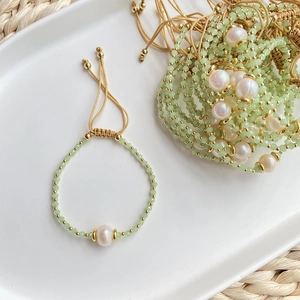 Detail of freshwater pearl and green crystal beaded bracelet on white ceramic tray