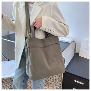 Army green nylon tote bag shown on a model in a professional minimalist setting