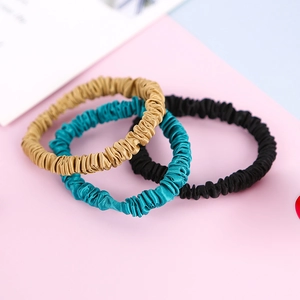 Three premium 22 momme mulberry silk scrunchies in gold, teal, and black silk satin finish
