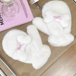 Dettaglio di muffole di peluche bianco con design a osso 3D e fiocco a scacchi rosa