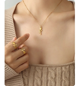 Detail of matte gold rose jewelry set featuring elegant floral necklace and matching rings