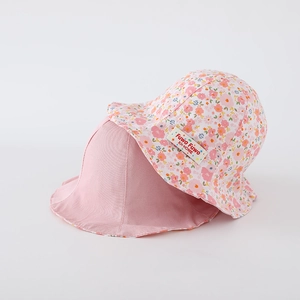 Détail d'un chapeau de soleil réversible pour bébé avec motif floral et logo de marque