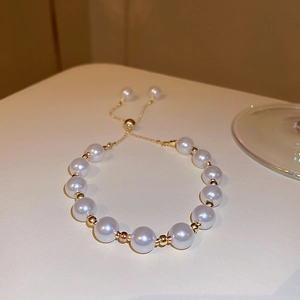 Detail of adjustable pearl bracelet with gold beads and a sliding metal clasp