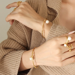 Retro style gold pearl bangle set and minimalist rings styled on warm knitwear