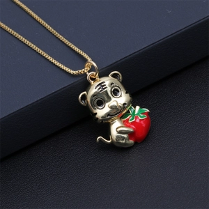 Detailed macro shot of a golden tiger pendant holding a red strawberry on a box chain