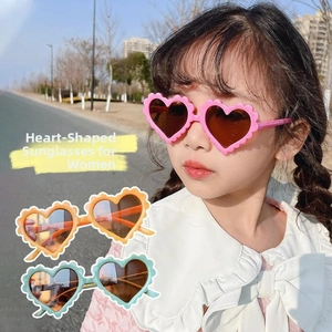 Detail of heart-shaped kids sunglasses with wavy frames in pink, yellow and green