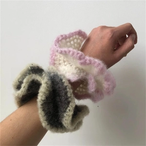 Detail of crochet ruffle scrunchies in gray and pink on wrist showing soft wool texture