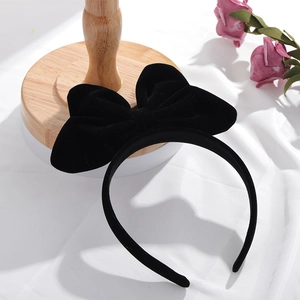 Détail d'un serre-tête nœud en velours noir sur un support en bois avec des roses