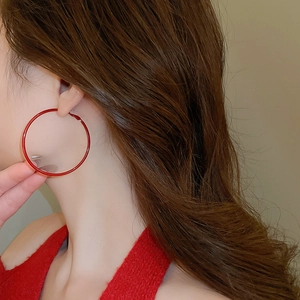 Close-up of minimalist Ancora red hoop earrings on model with high gloss finish