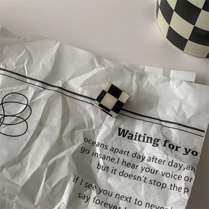 Macro detail of square black and white checkerboard hair clip on aesthetic text background