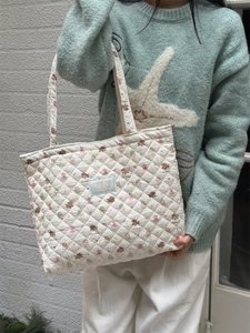 Detail of quilted tote bag with cute bear prints and blue studio brand label
