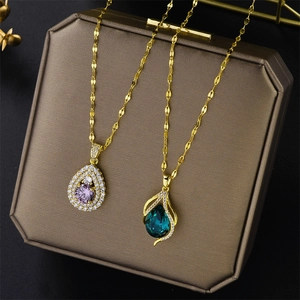 Gold titanium steel necklaces with teardrop purple and green zircon pendants on jewelry box