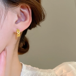 Close-up of 18k gold plated braided texture hoop earring worn on woman's ear