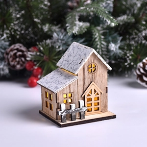 LED lit wooden Christmas house ornament with snow-dusted roof and warm light glow