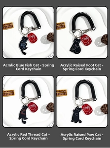 Detail view showing four black cat acrylic keychains with flexible black spring cords