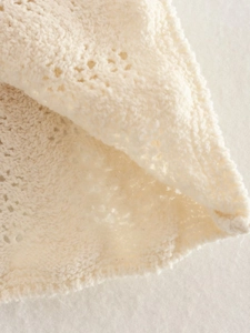 Dettaglio macro del tessuto a maglia traforata color crema con trama intrecciata fine