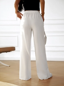 Rear view of white wide leg trousers featuring an elastic waistband and elegant drape