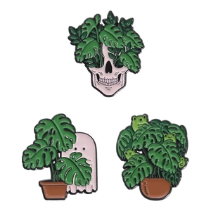 Three-piece enamel pin set featuring skeleton and ghost with green monstera plant motifs