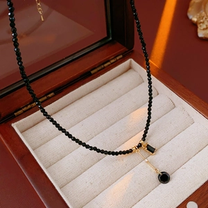 Detailed view of a black crystal beaded necklace with gold pendant in a wooden jewelry box