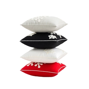Stacked Christmas snowflake embroidered cushion covers in grey, black, white, and red