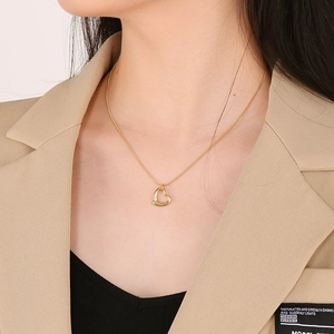 Close-up of a model wearing a gold hollow heart pendant on a sleek snake chain necklace