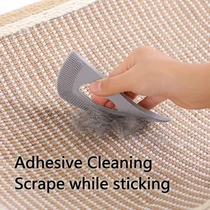 Manual pet hair remover tool scraping cat fur off a grey textured woven carpet