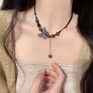 Close-up of ceramic butterfly pendant on black cord with tiger eye beads and metal tassel