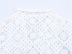 Detailed close-up of white hollow lace fabric with geometric diamond crochet patterns