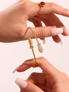Détail d'un bracelet ouvert poisson doré avec zircones et bague sertie de pierre rouge