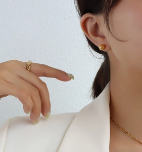 Gros plan détaillé de boucles d'oreilles boules dorées et bague texturée sur un mannequin
