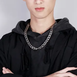 Close-up of a silver-tone chunky Cuban link chain necklace on a male model in black hoodie