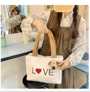 Detail of white faux fur tote bag featuring red heart LOVE print and plush dog pendant