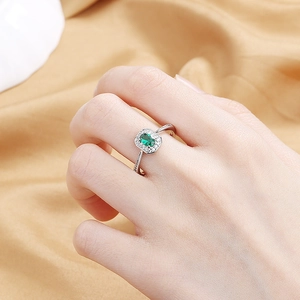 Elegant silver ring with oval green gemstone and diamond halo on champagne satin background
