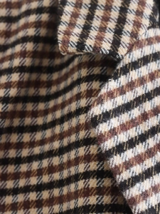 Makroaufnahme der Hahnentritt-Wollstofftextur auf einem Damenblazer im Vintage-Stil
