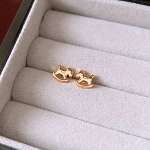 Close-up of 18K gold-plated rocking horse stud earrings on a velvet jewelry display